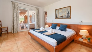 A spacious bedroom with a large bed, a wooden headboard, a painting on the wall, and a view through the glass door. - Villa in Javea, on the Costa Blanca, Spain with private pool for 6 persons (Javea)