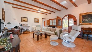 A spacious living room with wooden beams, a white sofa, a coffee table, and a white armchair. - Villa in Javea, on the Costa Blanca, Spain with private pool for 6 persons (Javea)