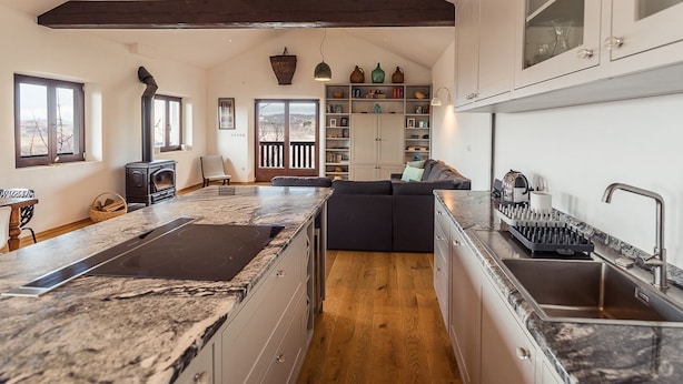 Een ruime keuken met een groot eiland, houten balken en uitzicht op de omgeving.