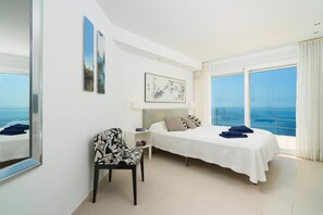 A hotel room with a bed, a chair, a nightstand, and a large window offering a view of the sea. - Villa Bombon - Javea, Costa Blanca (Javea)