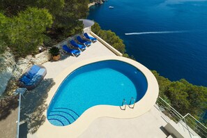 A swimming pool with a view of the sea, surrounded by lounge chairs and a stone wall. - Villa Bombon - Javea, Costa Blanca (Javea)