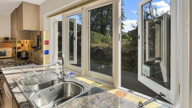 A modern kitchen with a large island, stainless steel appliances, and a colorful backsplash. - Forge Cottage, Wootton Courtenay (Wootton Courtenay)