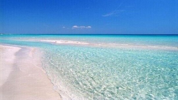 Une plage à l’eau turquoise et au sable blanc.