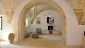 Une pièce avec des arches en pierre, une cheminée, un lit et une chaise.