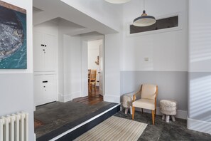 A modern interior with a wooden floor, a white door, a chair, and a small table.