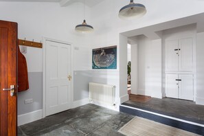 A hallway with a white door, a radiator, and a painting on the wall.