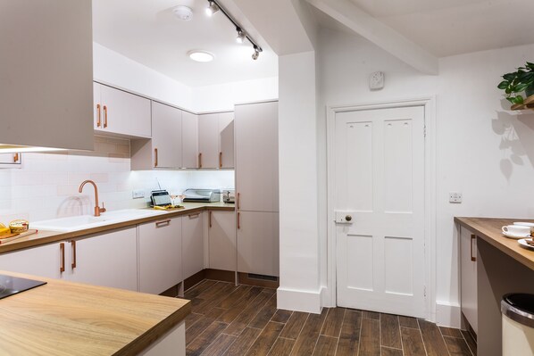 A modern kitchen with white cabinets, a wooden countertop, and a built-in oven.
