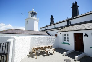 A white building with a wooden bench, a door, and a window.