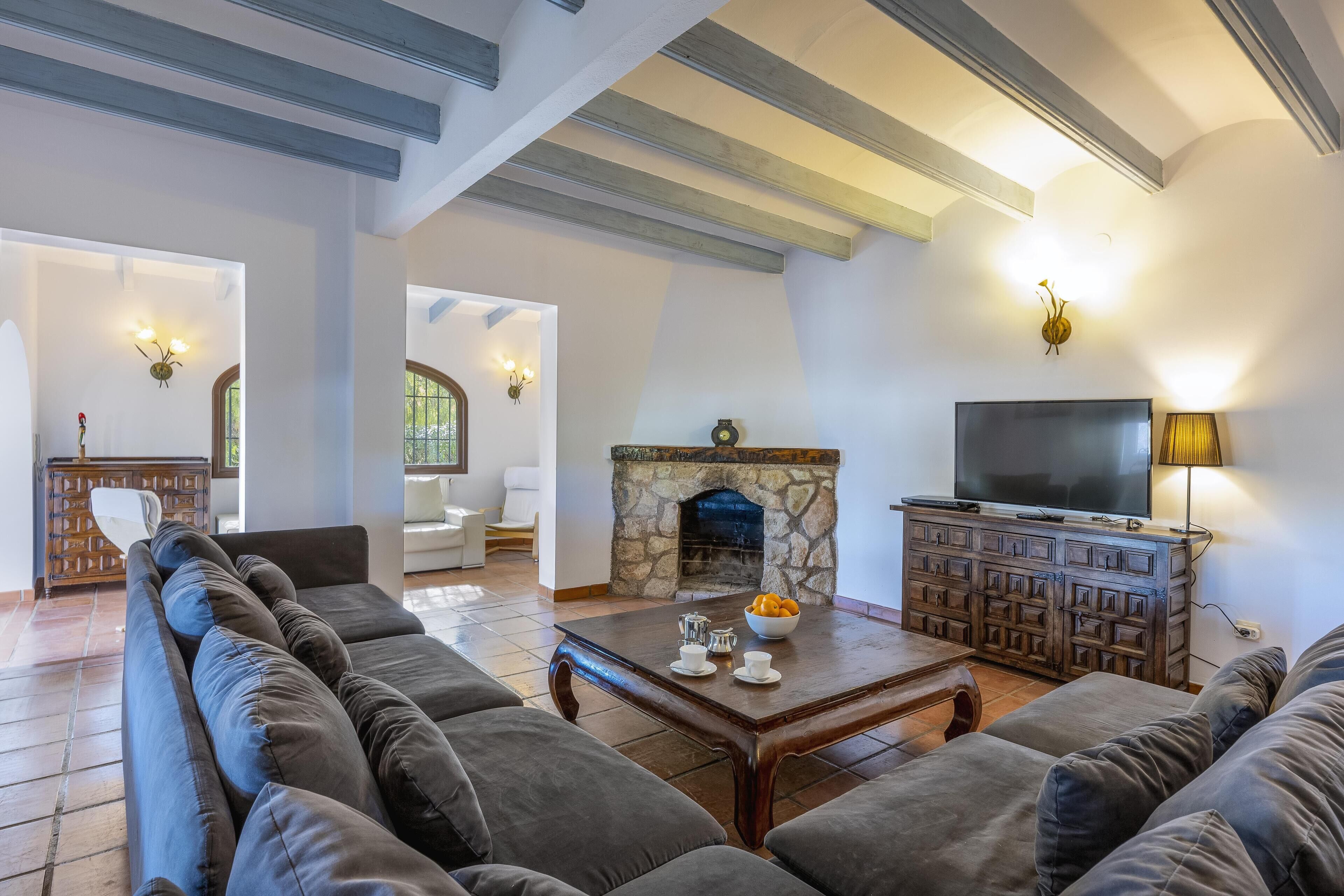 A spacious living room with a stone fireplace, a television, and a comfortable seating area.