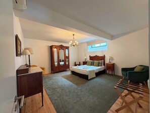 Une chambre à coucher comprenant un lit, une armoire, un bureau, une chaise, une petite table et une fenêtre.