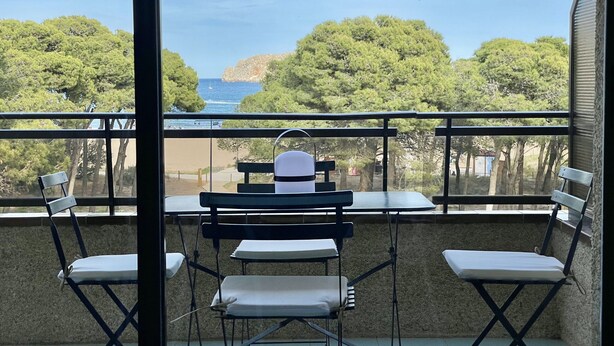 Ein Balkon mit Meerblick, ausgestattet mit Klappstühlen und einem Tisch.