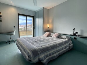 A bedroom with a bed, a desk, a chair, a nightstand, and a window with a view. - Beautiful apartment in front of the sea (Estartit)