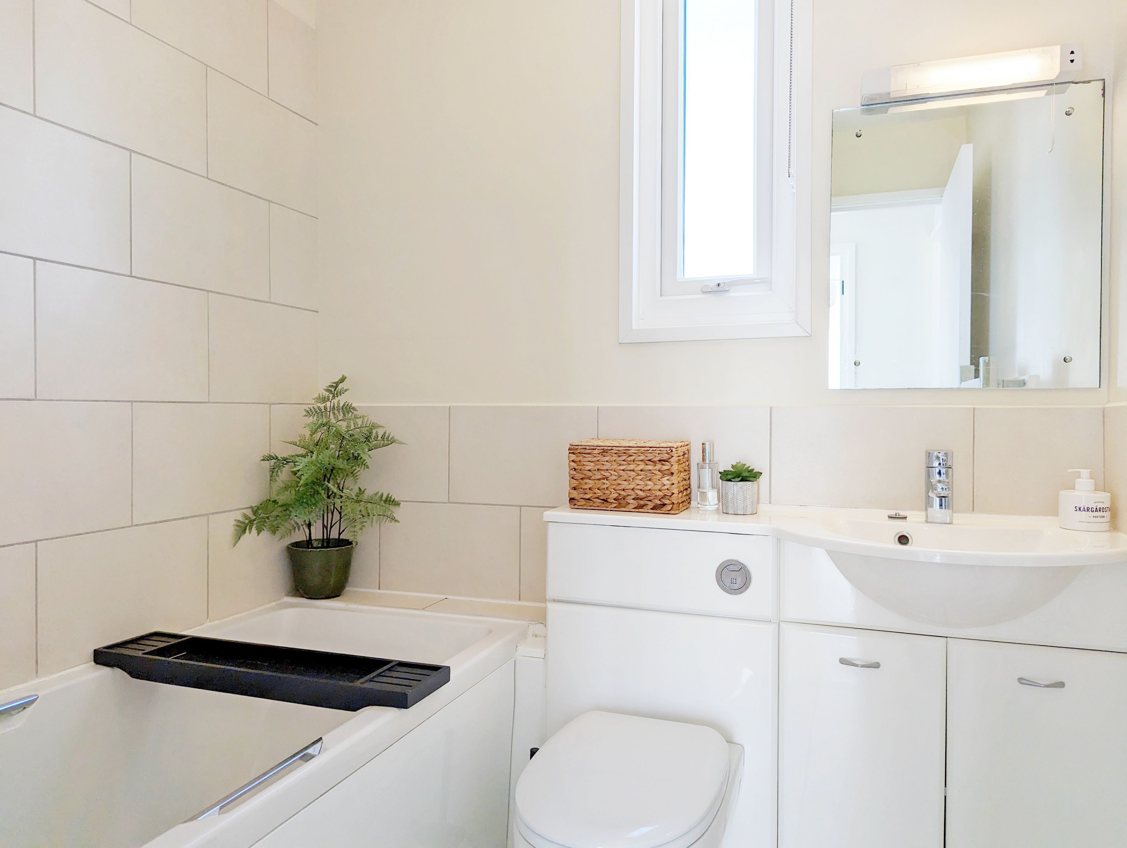 A modern bathroom with a bathtub, toilet, sink, and a mirror above the sink.
