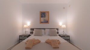 Een hotelkamer met een bed, twee nachtkastjes met lampen, een schilderij aan de muur en handdoeken op het bed.