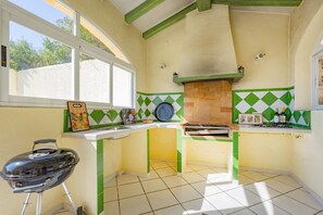 A kitchen with a grill, a window, and a tiled backsplash.
