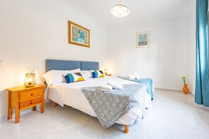 A neatly arranged bedroom with a large bed, bedside tables, and a nightstand.
