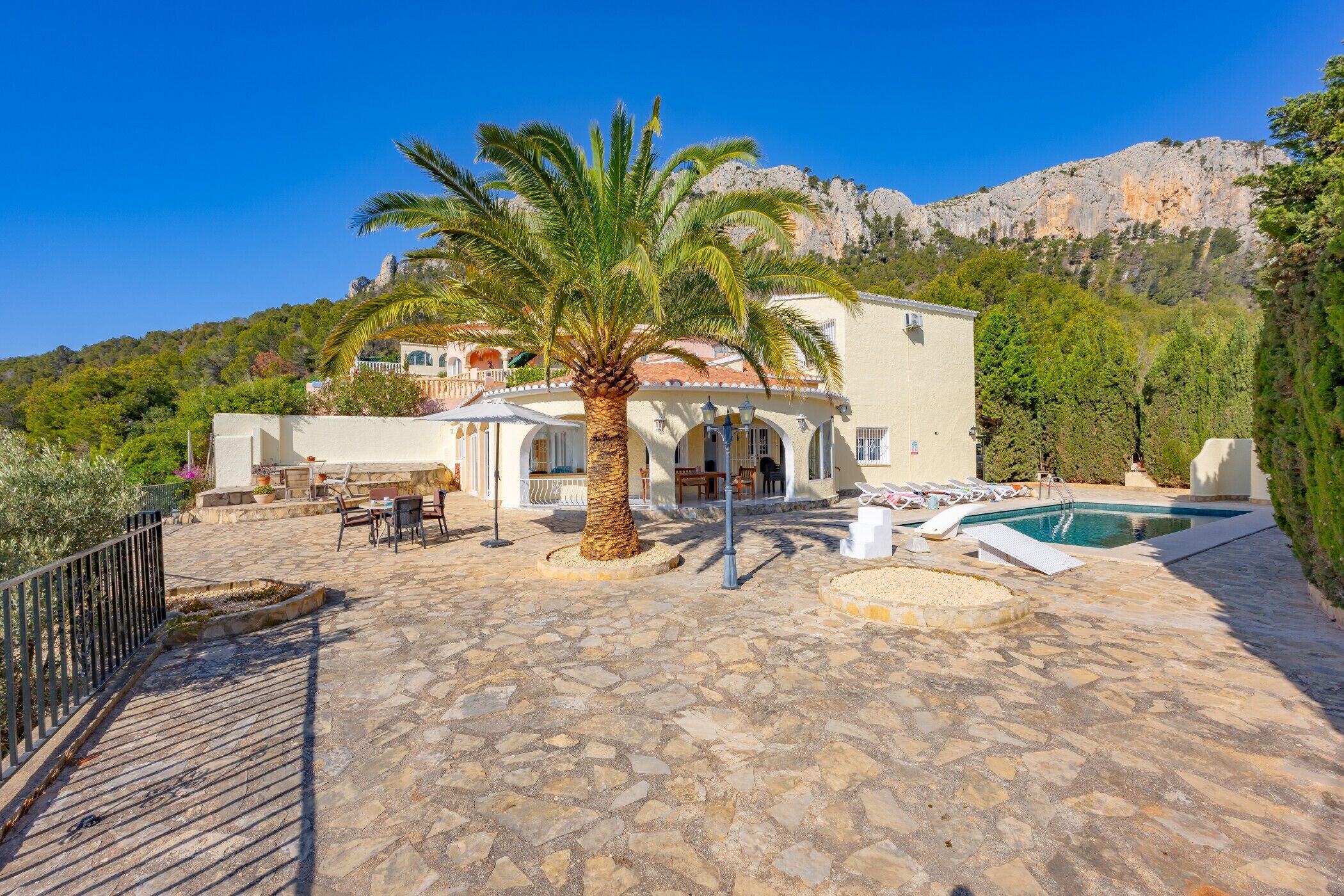 A villa with a pool, outdoor seating, and a mountain backdrop.