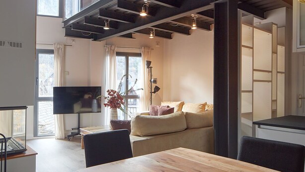 A modern living room with a wooden dining table, sofa, and a TV. - Val Arties 2 by FeelFree Rentals (Arties)
