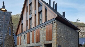 A modern building with a stone facade and wooden accents, featuring a prominent entrance and large windows. - Val Arties 2 by FeelFree Rentals (Arties)