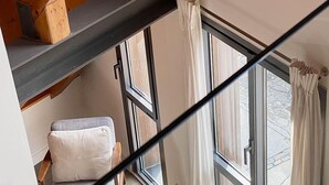 A room with a loft bed, a small table with cups, and a window with curtains. - Val Arties 2 by FeelFree Rentals (Arties)