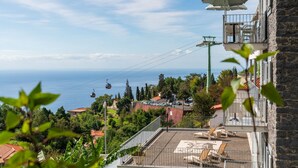Vue d’une zone côtière avec un téléphérique, une terrasse sur le toit dotée de chaises longues et un bâtiment en pierre avec un balcon.