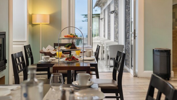 Une table dressée pour le petit-déjeuner, avec un plateau à trois niveaux, un panier et une carafe de jus d’orange.