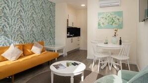 Un salon avec un canapé, une table à manger et des chaises, un téléviseur et un tableau accroché au mur.
