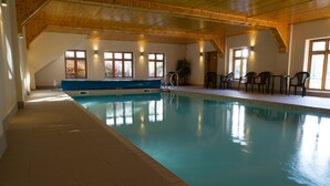 An indoor swimming pool with a blue bench, chairs, and tables. - Allerford Cottage, Near Dunster (Near Dunster)