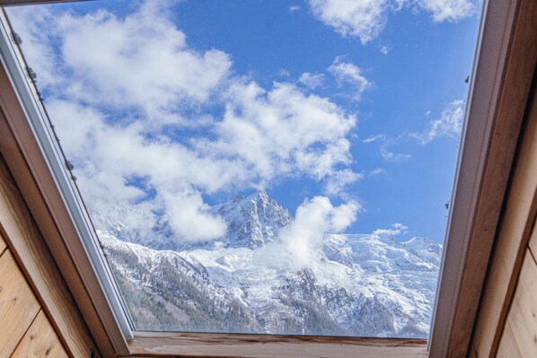 A skylight with a view of snow-covered mountains and a clear blue sky.