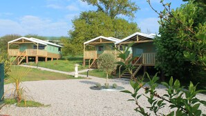 A row of cabins with wooden decks and a gravel path leading to them. - 2 bedroom luxury lodge with heated covered pool (Henansal)