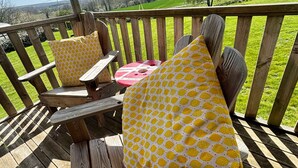 A wooden deck with two chairs and a table, overlooking a green landscape. - 2 bedroom luxury lodge with heated covered pool (Henansal)