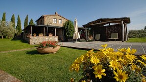 Un bâtiment en pierre doté d’un patio couvert et d’un espace extérieur aménagé pour s’asseoir.