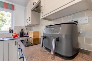 A kitchen with a built-in coffee machine, a wooden cutting board, and a bowl of fruit on the counter.