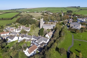 Une vue aérienne d’un village avec une église imposante, des maisons d’habitation et des champs verdoyants.
