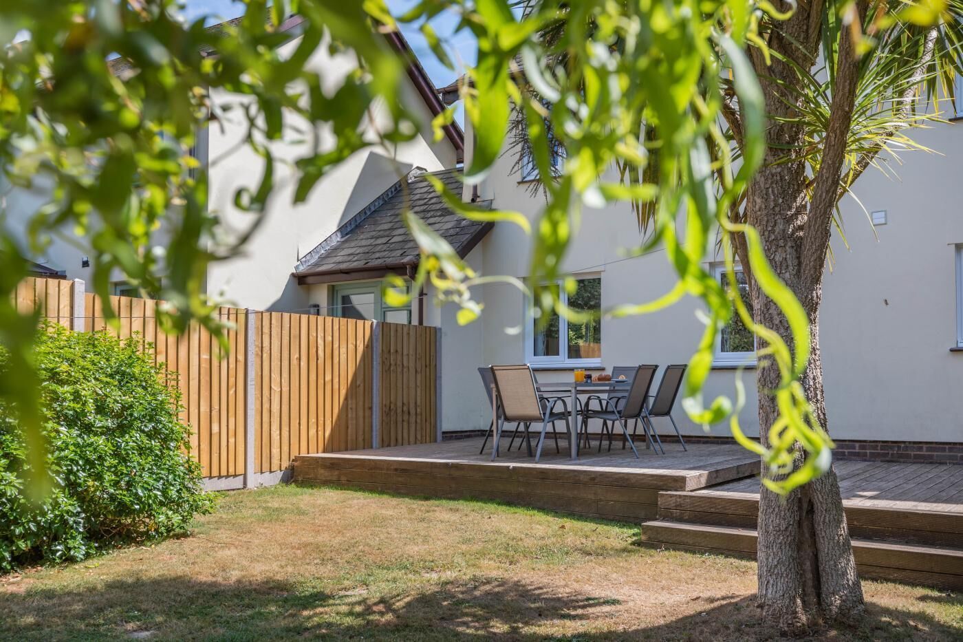 Il s’agit d’une propriété résidentielle dotée d’une terrasse, d’une table à manger avec des chaises, d’une clôture en bois et d’un arbre.
