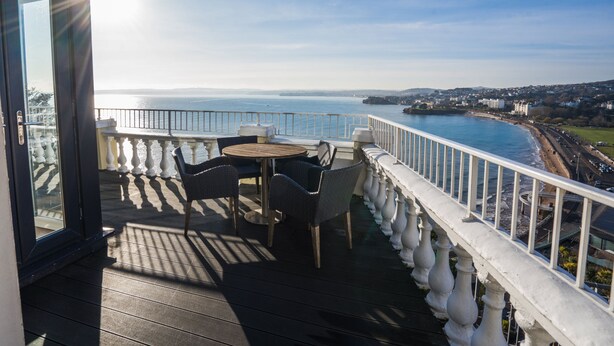 Ein Balkon mit Tisch und Stühlen und Blick auf die Küste.