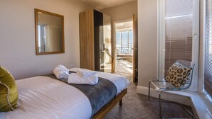 Ein Hotelzimmer mit Bett, Stuhl, einem Fenster mit Jalousien und einer Tür zum Balkon.