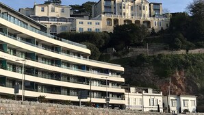 Ein mehrstöckiges Hotel mit modernem Design, das Balkone und eine Steinfassade aufweist.