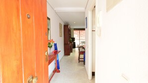 Un pasillo con una puerta de madera, un comedor con mesa y sillas, y vistas al exterior.