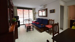 Una sala de estar con sofá, sillas, una mesa y un balcón con vistas.