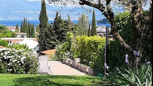 A garden with a patio area, potted plants, and a view of the sea and buildings in the background.