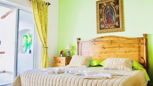 Ein Bett mit Holz-Kopfteil, einer grünen Wand und einem Bild darüber.