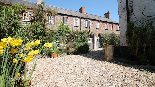A stone building with a gravel driveway and potted plants. - Grace Cottage, Porlock (Porlock)