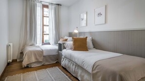 A bedroom with two beds, a bedside table, a lamp, and a radiator. - Era Solana by FeelFree Rentals (Vielha)