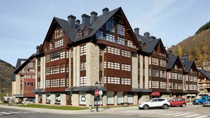 A large, multi-story building with a traditional architectural style, featuring stone and wood construction, large windows, and multiple chimneys. - Era Solana by FeelFree Rentals (Vielha)