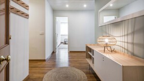 A hallway with wooden flooring, a round woven rug, a wooden console table with a lamp, and a mirror on the wall. - Era Solana by FeelFree Rentals (Vielha)