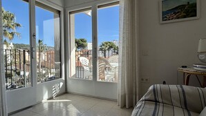 A room with a balcony, a bed, and a painting. - APARTAMENT GRECIA (Estartit)