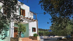 A two-story building with a white facade and green trim, a wooden pergola, and a gravel driveway. - Villa near Almyrida ☀️ Private Pool Gated For Child Safety ☀️ FREE WiFi (Old Road, Gavalochori - Almyrida)