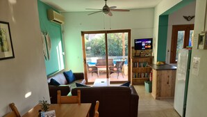 A cozy living area with a wooden table, a sofa, and a bookshelf. - Villa near Almyrida ☀️ Private Pool Gated For Child Safety ☀️ FREE WiFi (Old Road, Gavalochori - Almyrida)