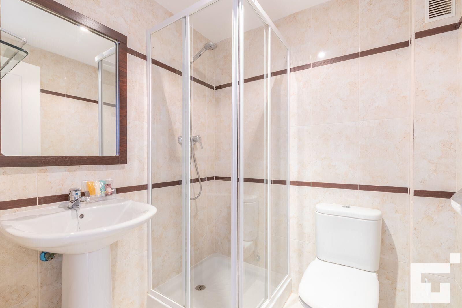 Une salle de bain avec une douche à parois de verre, un lavabo et des toilettes.